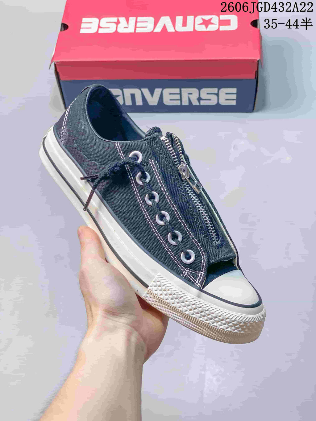 Angled view of a black Converse low-top sneaker with a central zipper and off-white sole.