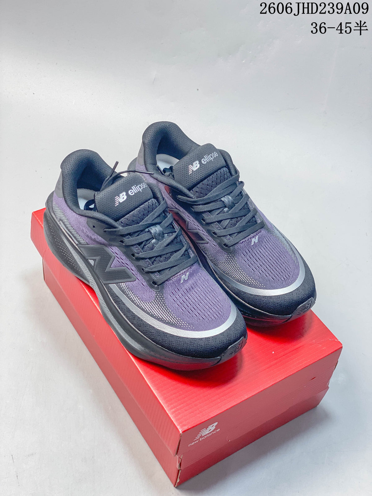 Pair of purple, gray, and dark navy New Balance Ellipse shoes on a red box