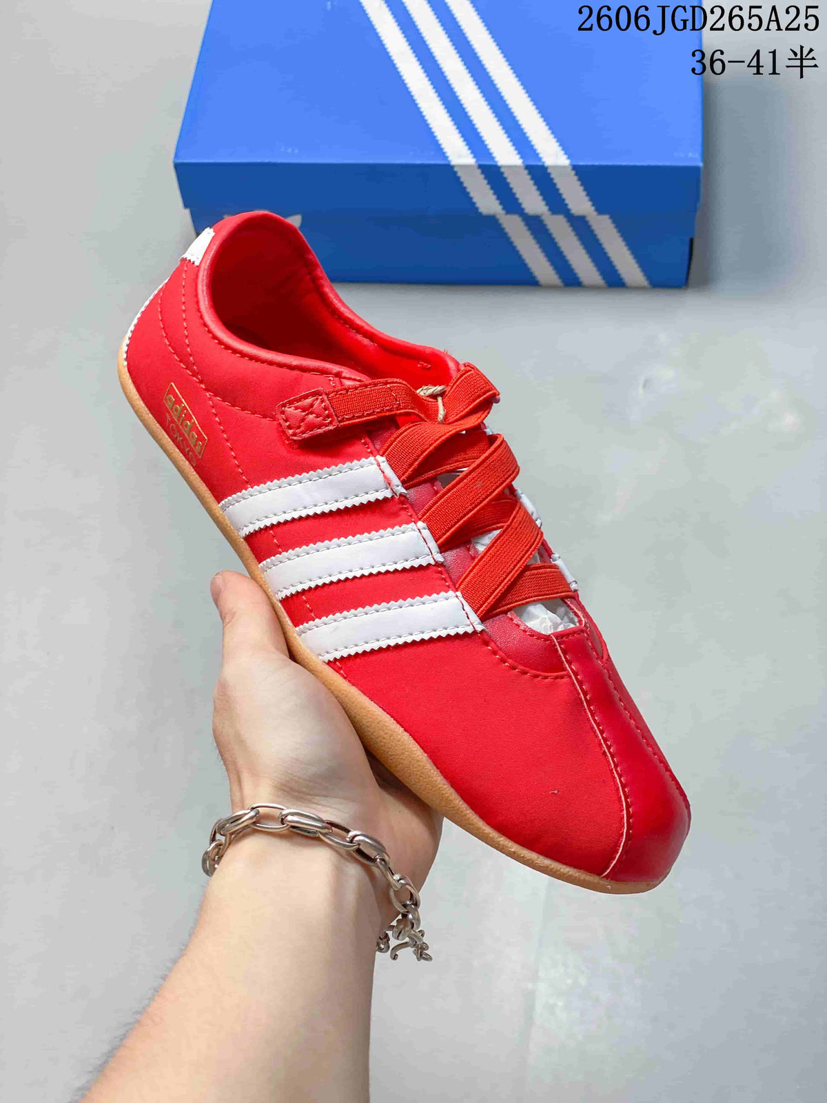 Close-up of a red Adidas Tokyo W sneaker with white side stripes, crossing bands, and a gum-colored outsole.
