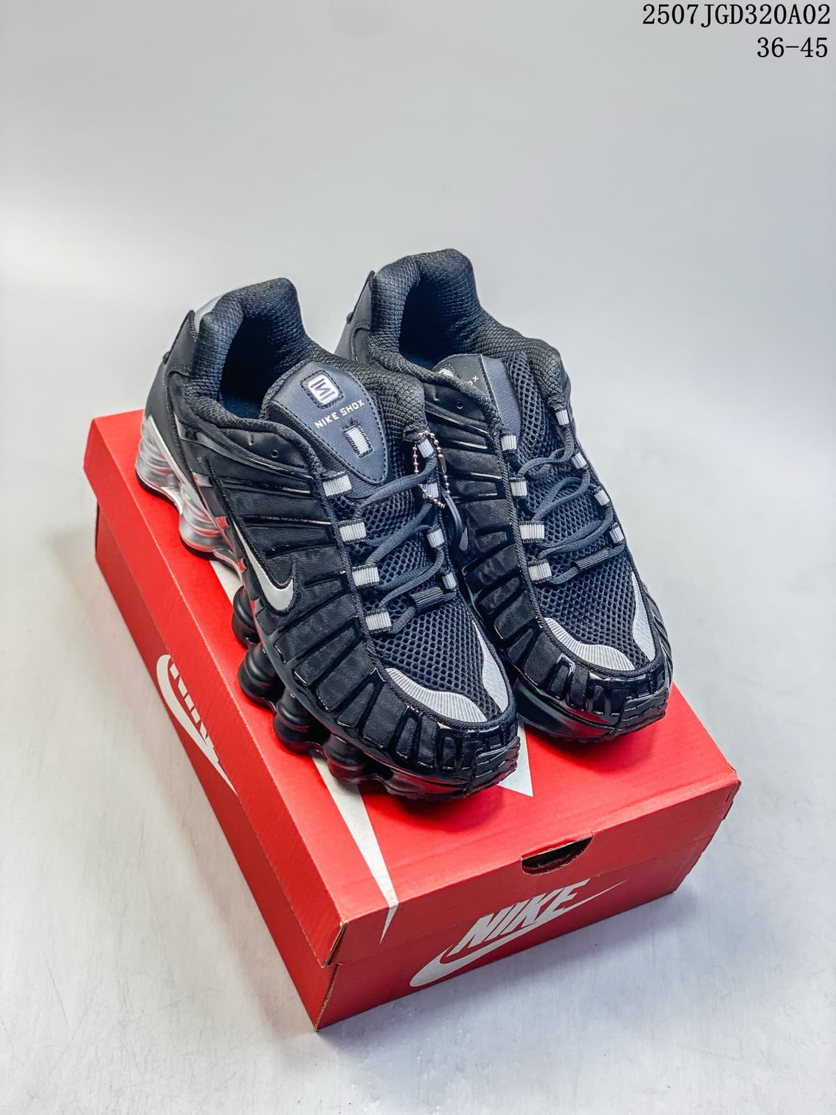 Black and silver Nike Shox TL sneakers displayed on a red shoe box