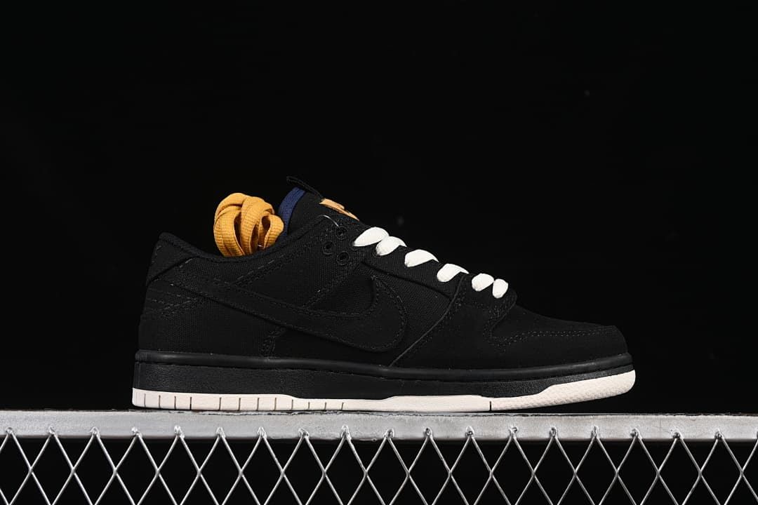 Side profile of a black low-top sneaker with a swoosh, white laces, and light outsole