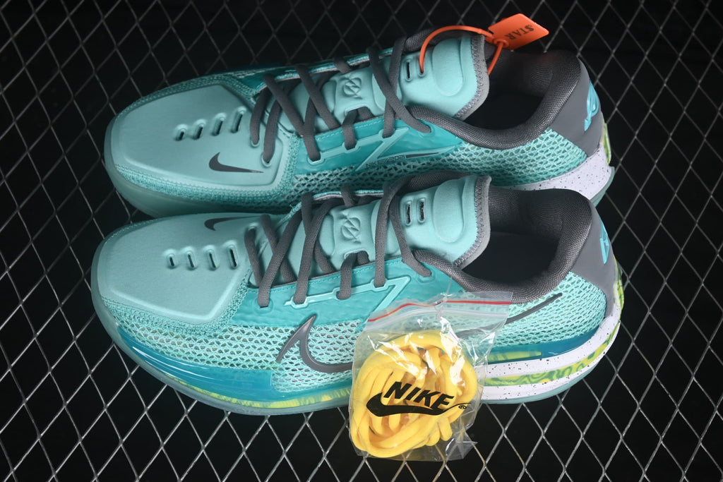 Pair of turquoise Nike basketball shoes with gray laces, orange accents, and a translucent outsole shown from above.