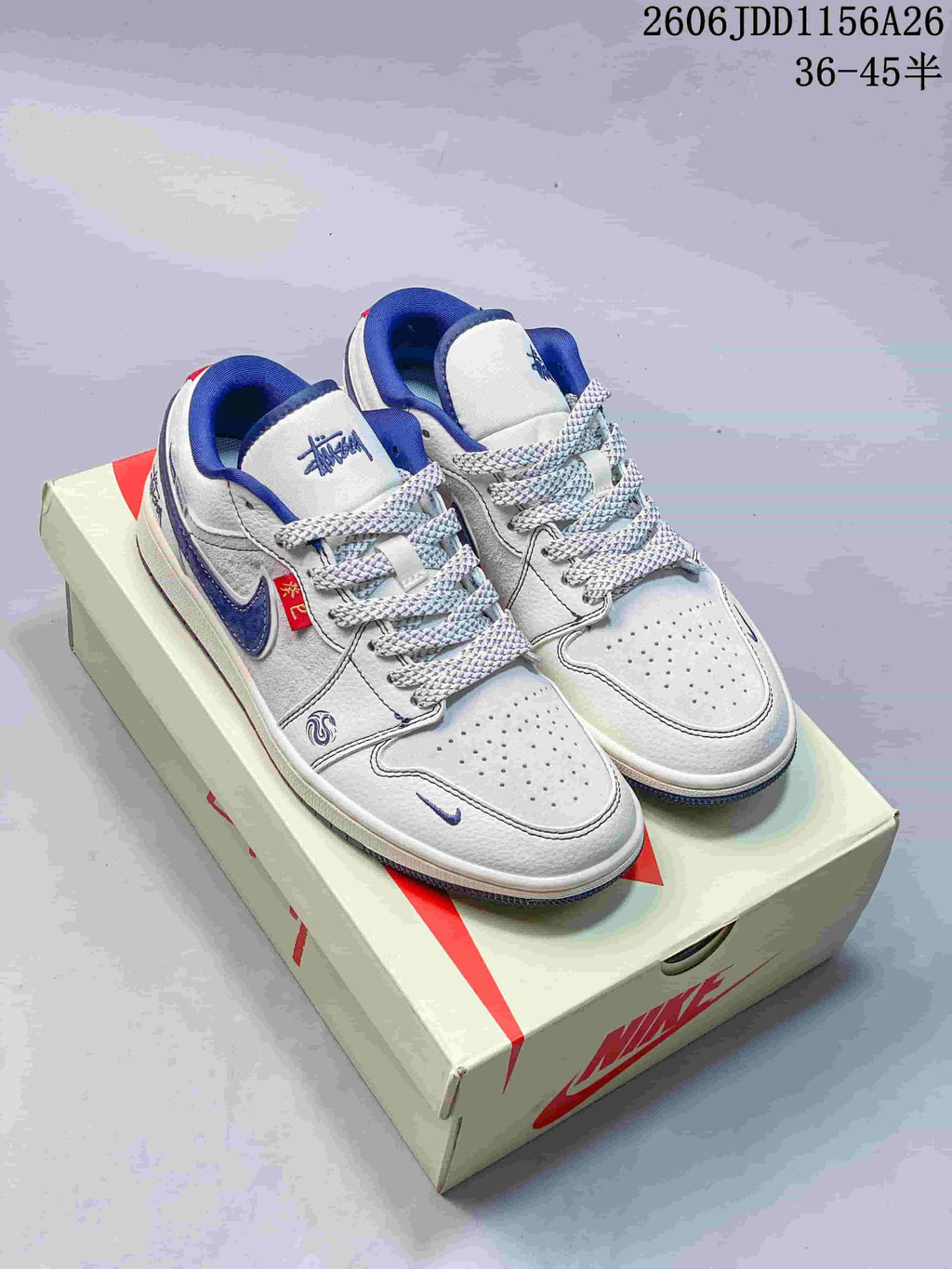 Pair of white and blue low-top sneakers with perforated toes and contrast laces on a shoebox.