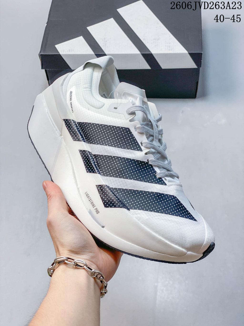 Side view of a white Adizero Dropset Elite shoe with dark stripes and light gray details.
