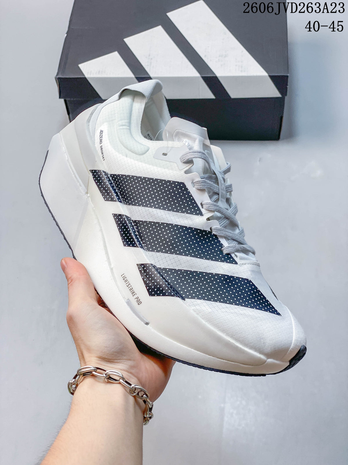 Side view of a white Adizero Dropset Elite shoe with dark stripes and light gray details.