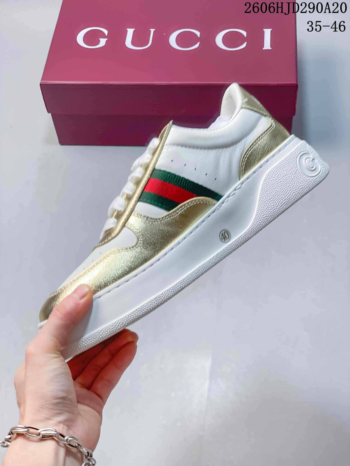 Side profile showing the white upper, gold-tone overlays and green-and-red stripe