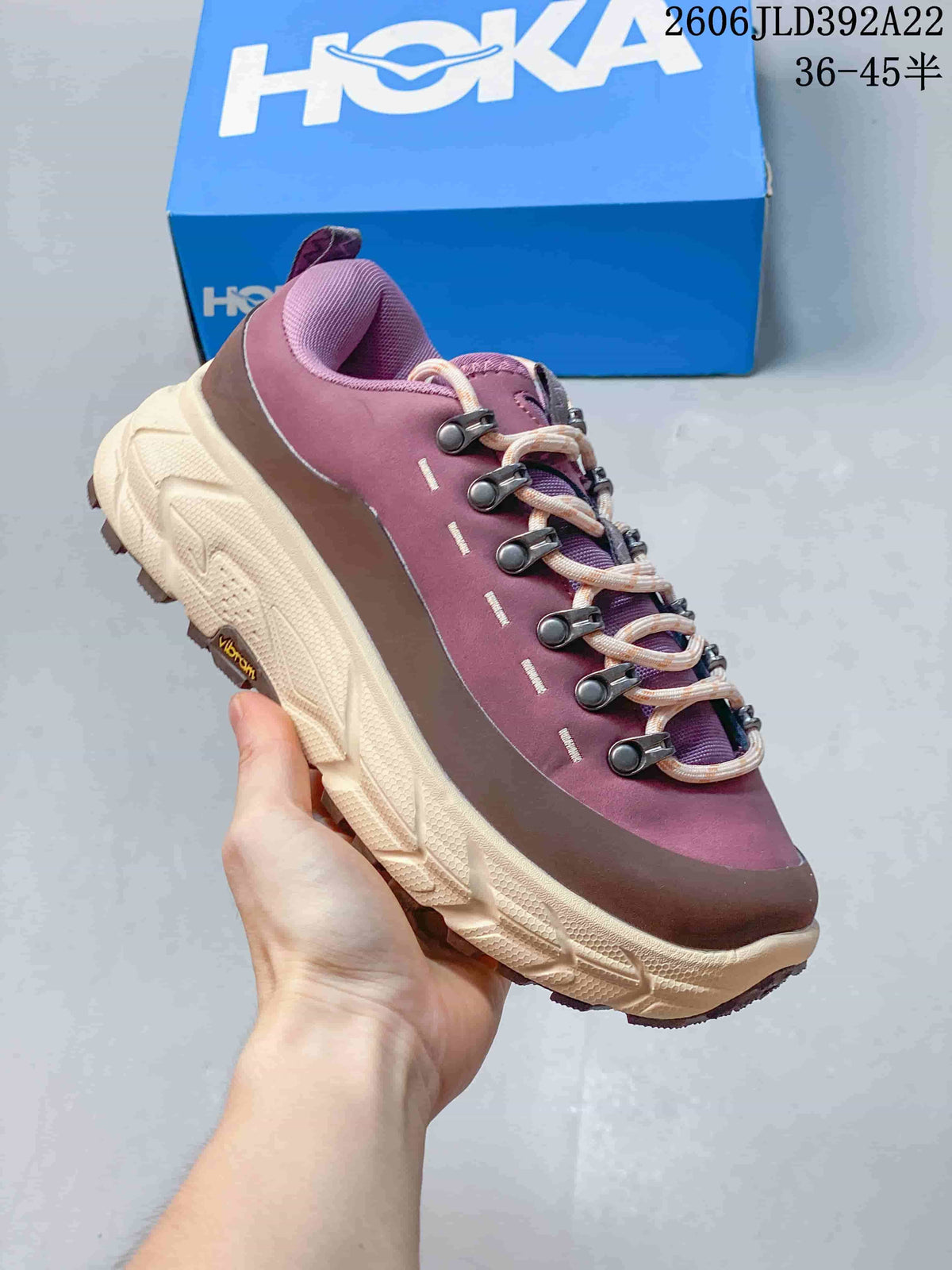 Side view of a plum and cream HOKA low-top sneaker showing its chunky outsole and lace hardware