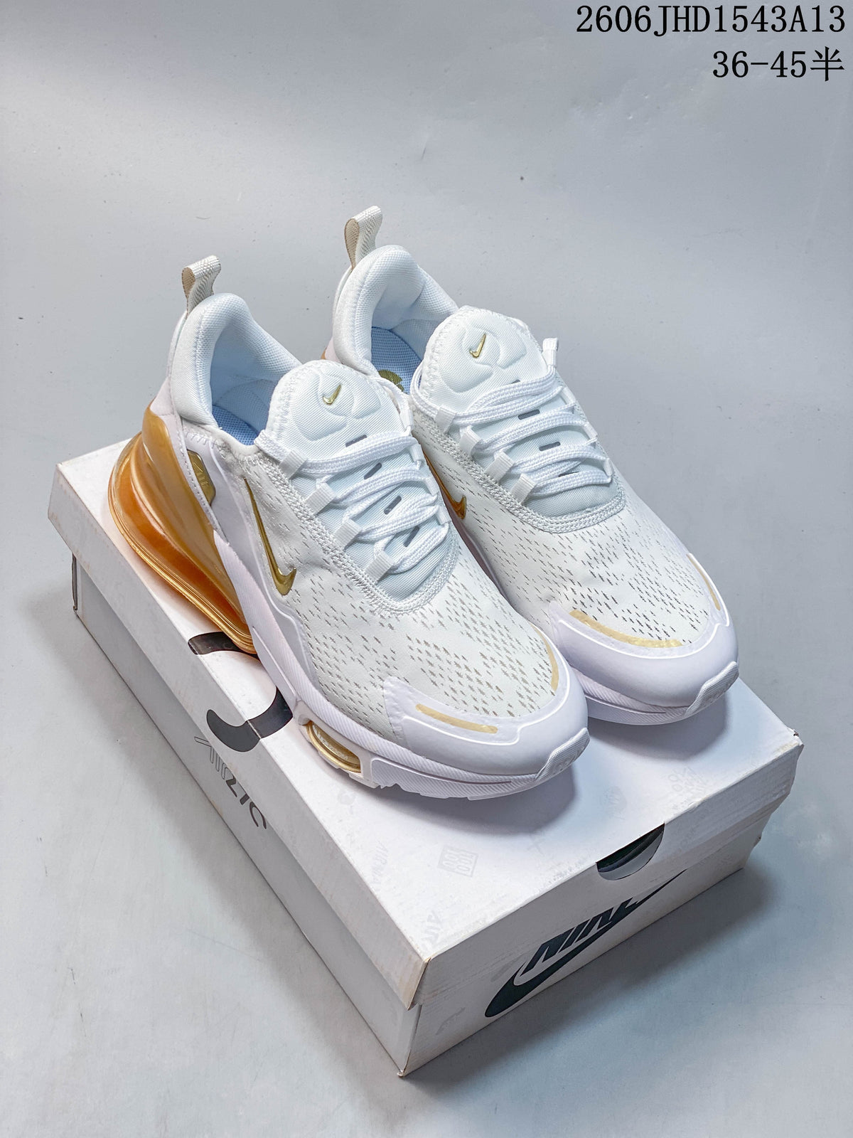 Pair of white Nike Air Max 270 sneakers with gold-colored details and amber heel units