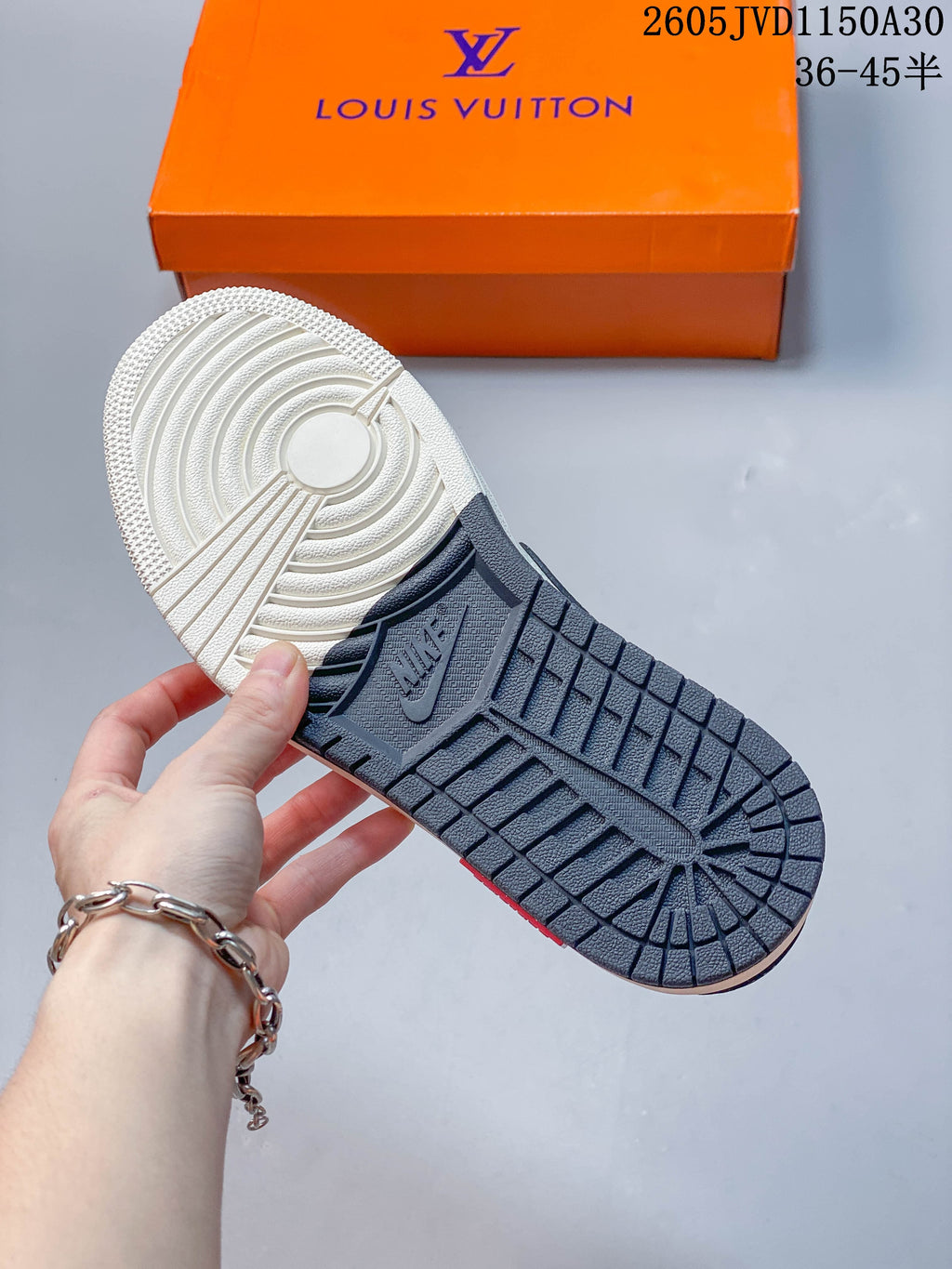 View of the sneaker outsole, with an off-white forefoot and dark patterned heel section.