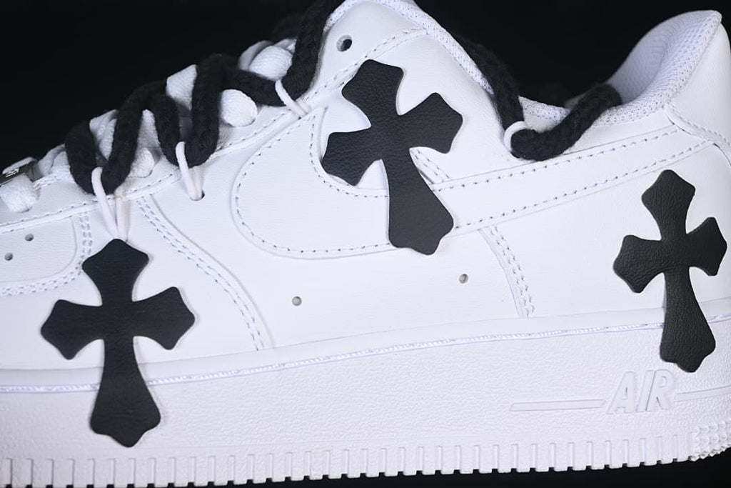 Close-up of the white sneaker's side, black cross appliqués, and laces.