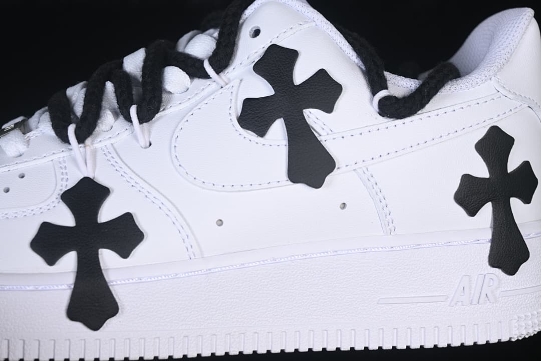 Close-up of the white sneaker's side, black cross appliqués, and laces.