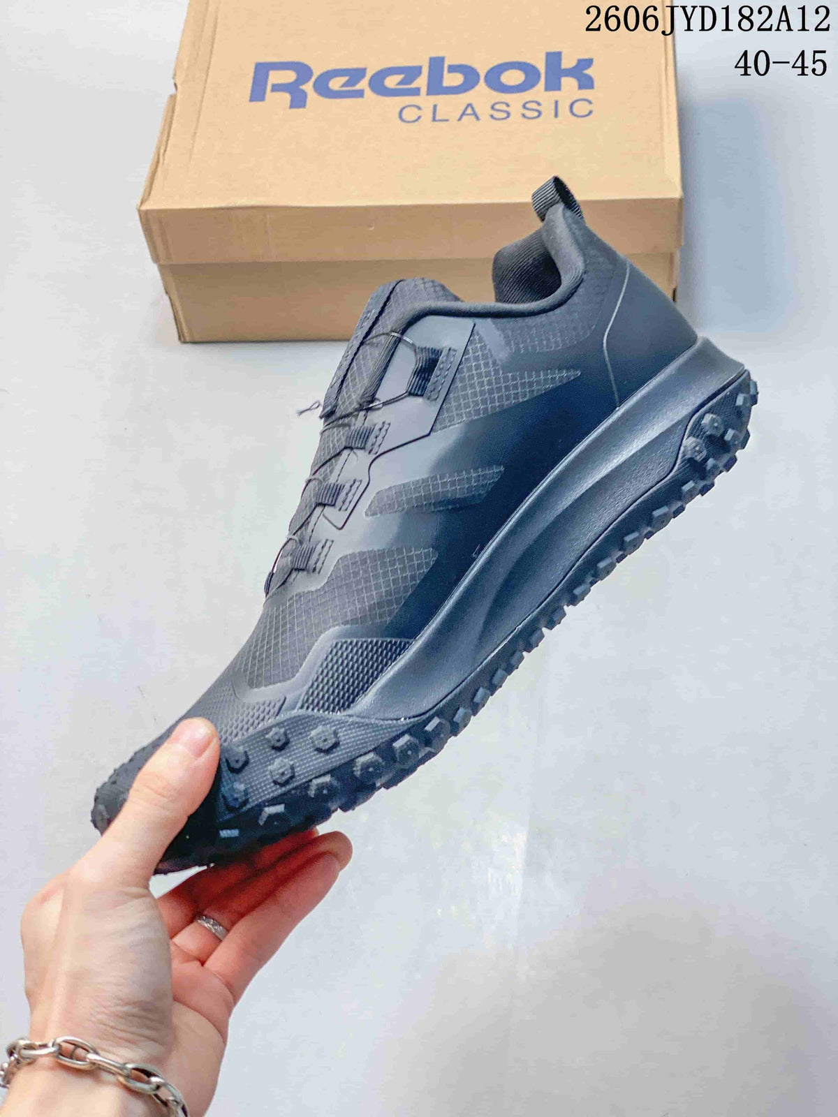 Side profile of a charcoal sneaker with cord-style lacing and a textured outsole.