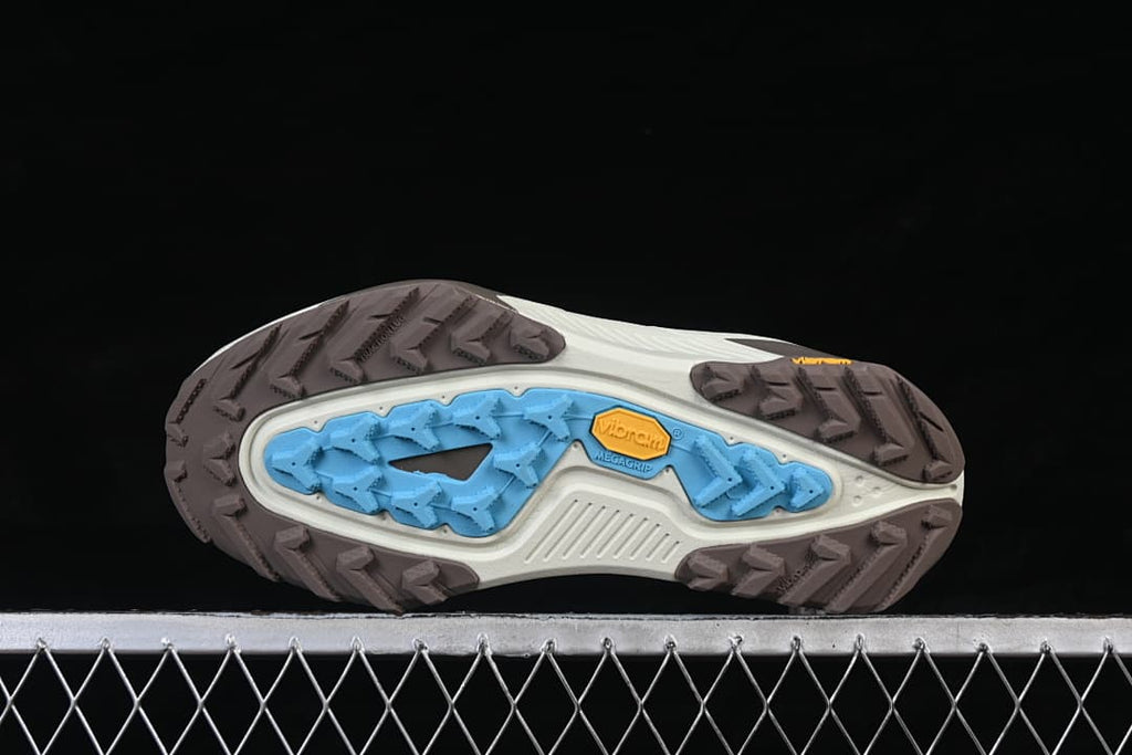 Underside view showing the trail outsole with multidirectional lugs and colored tread sections.