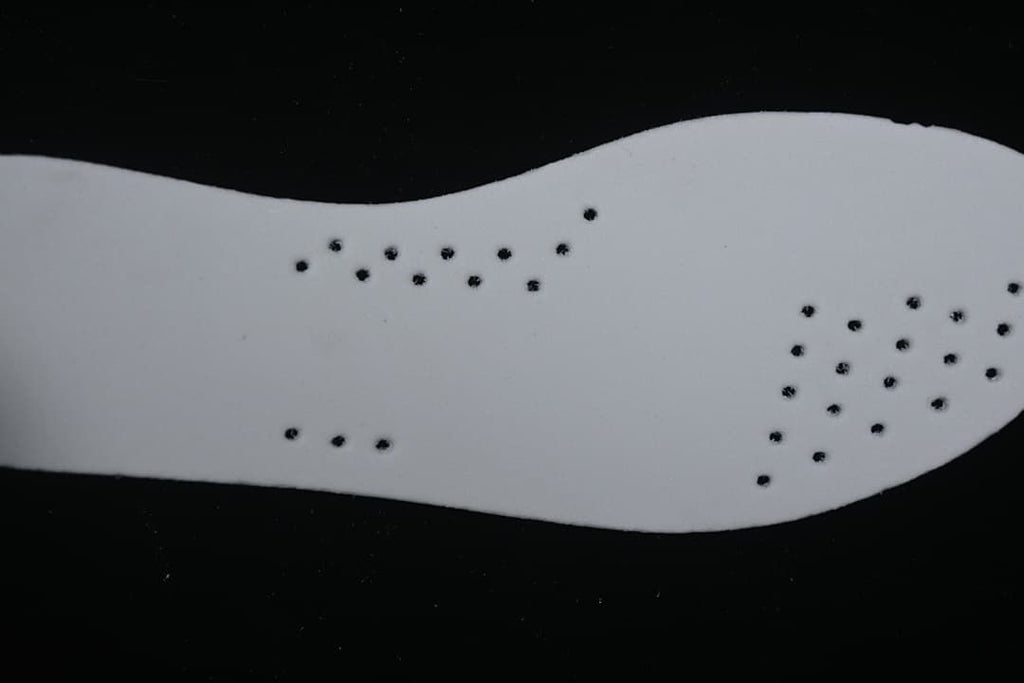 Close-up of a white shoe insert with small perforations