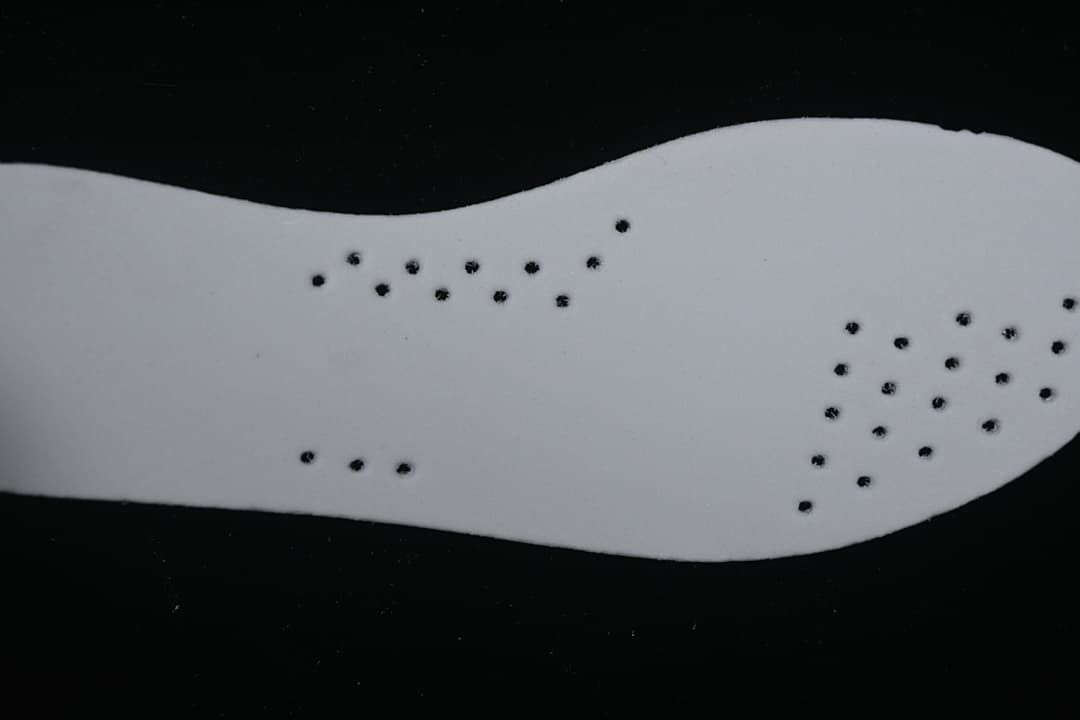 Close-up of a white shoe insert with small perforations