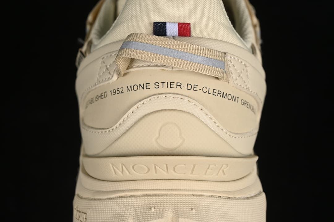 Rear view of the beige sneaker with heel branding and a small tricolor flag detail.