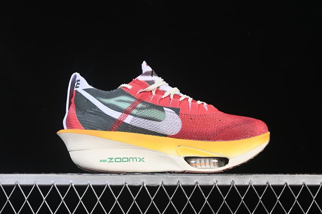 Side profile showing the shoe’s red and dark green upper and yellow-edged sole