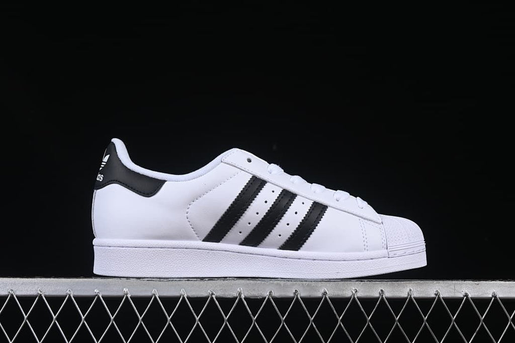 Side profile of a white sneaker with black stripes and shell toe