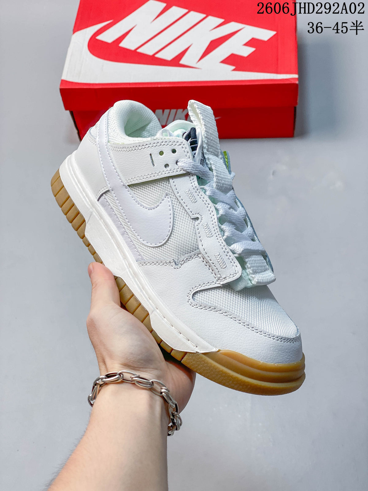 White Nike SB Dunk low-top sneaker with a gum-colored outsole, shown beside a Nike shoe box.