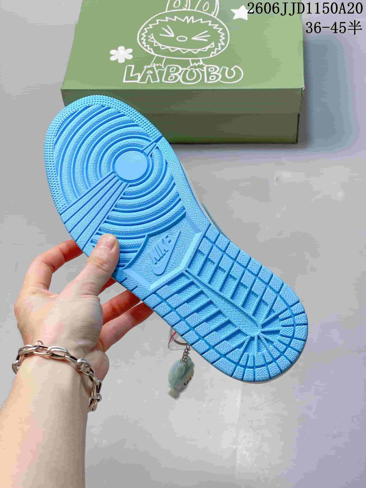 Blue patterned outsole of the sneaker, with a green character-printed box in the background.