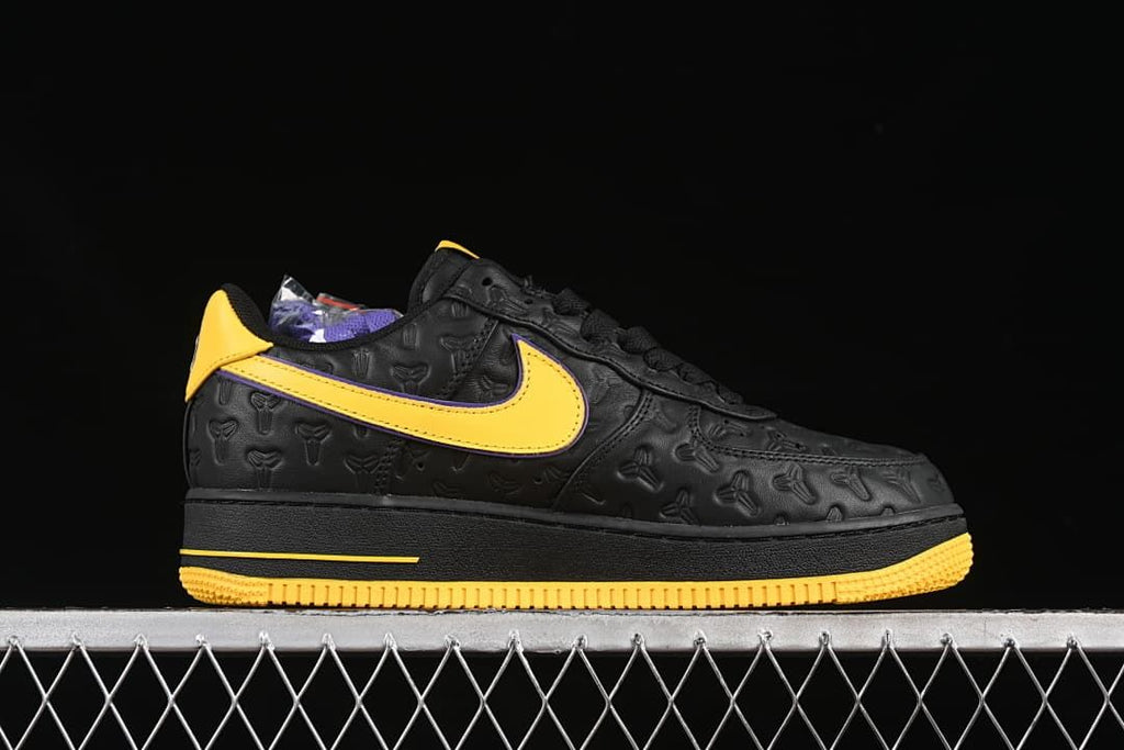 Side profile of the sneaker with yellow Swoosh, purple trim, and black embossed upper.