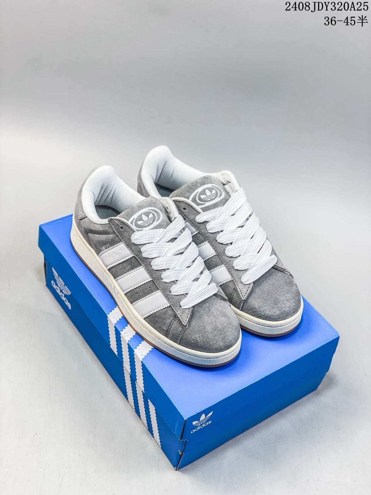 Pair of grey Adidas Campus sneakers with white stripes and laces on a blue box