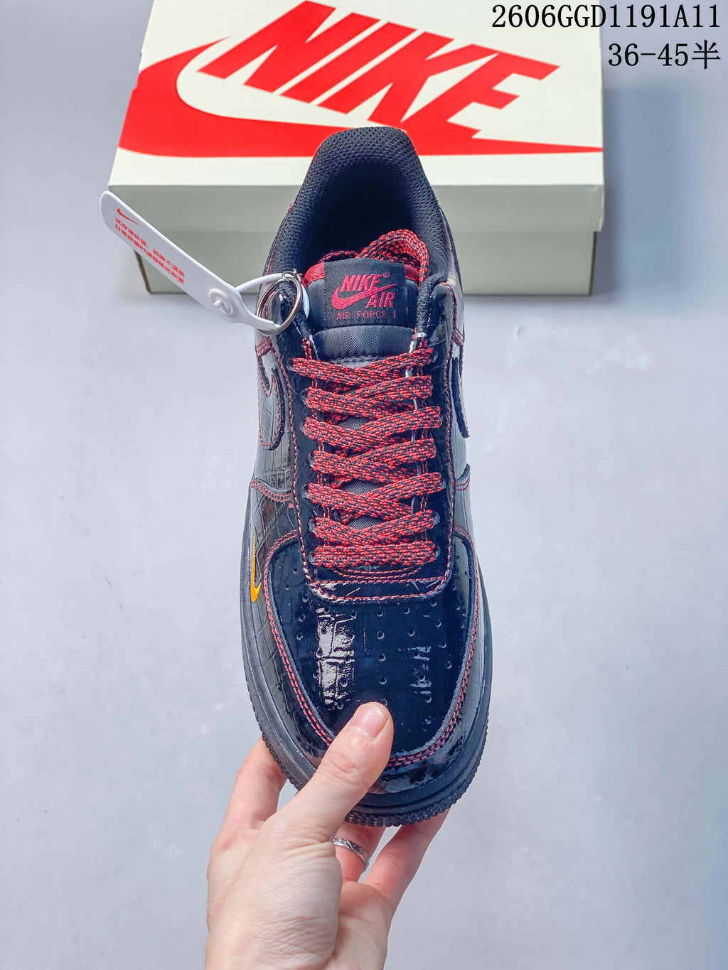 Front view showing the perforated toe, red-and-black laces, and dark glossy finish