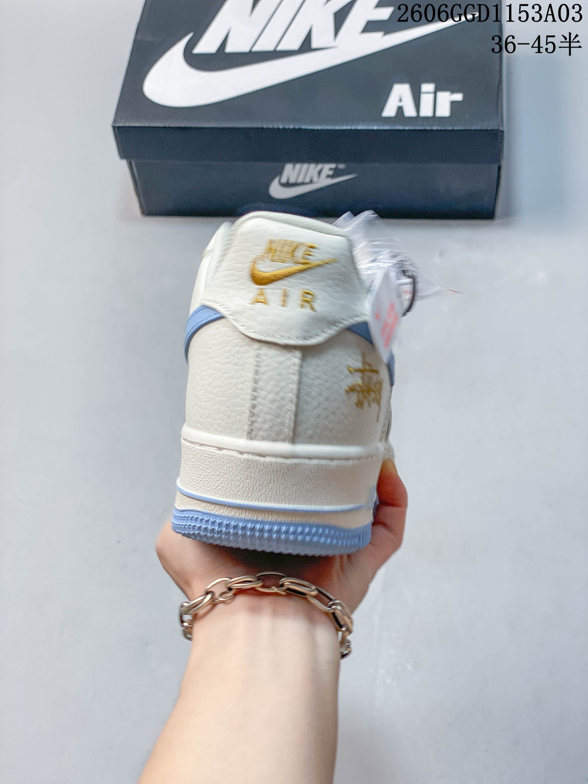 Rear view of an off-white sneaker with gold-tone detailing and light blue outsole