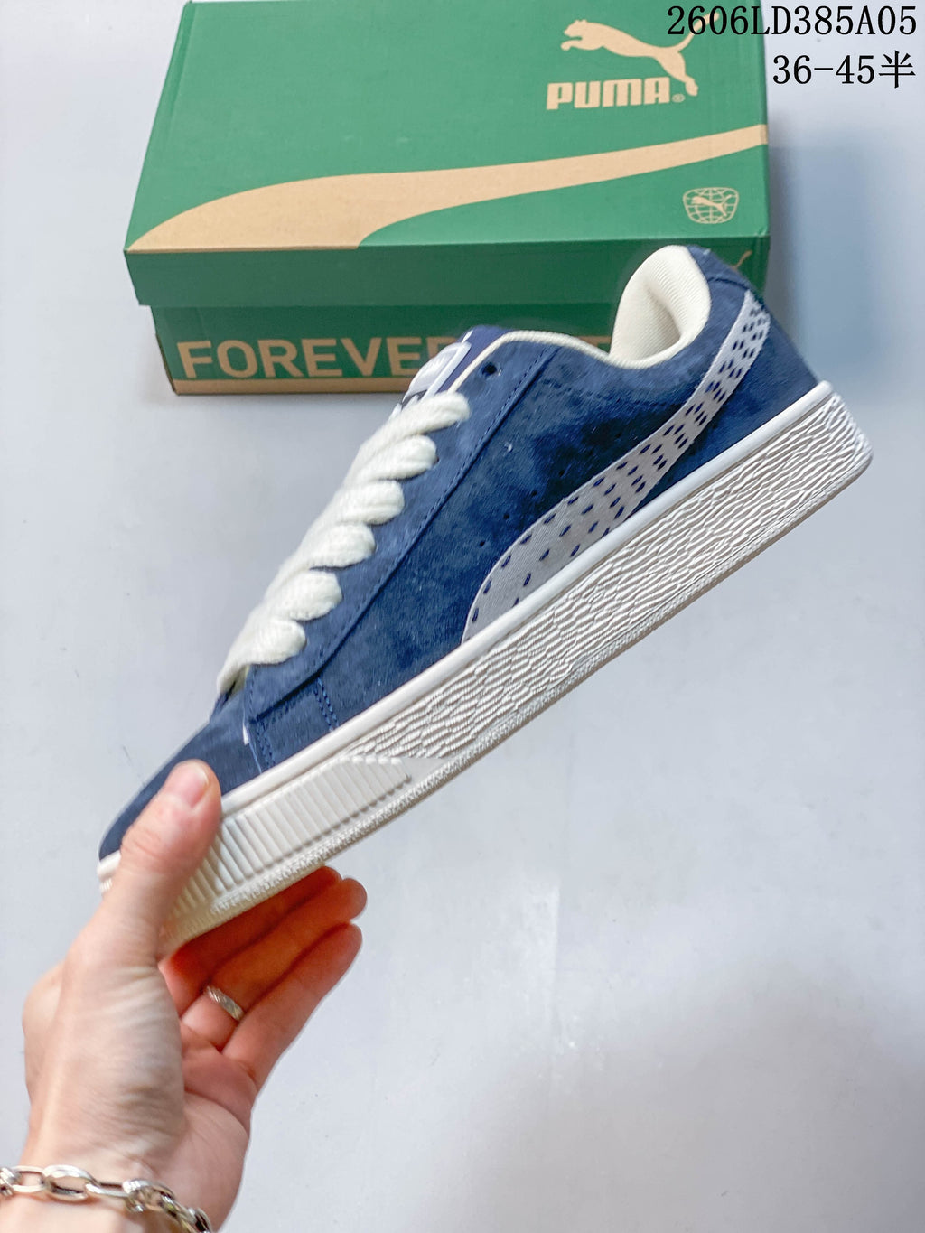 Side view of a blue PUMA sneaker with a patterned stripe and off-white sole.