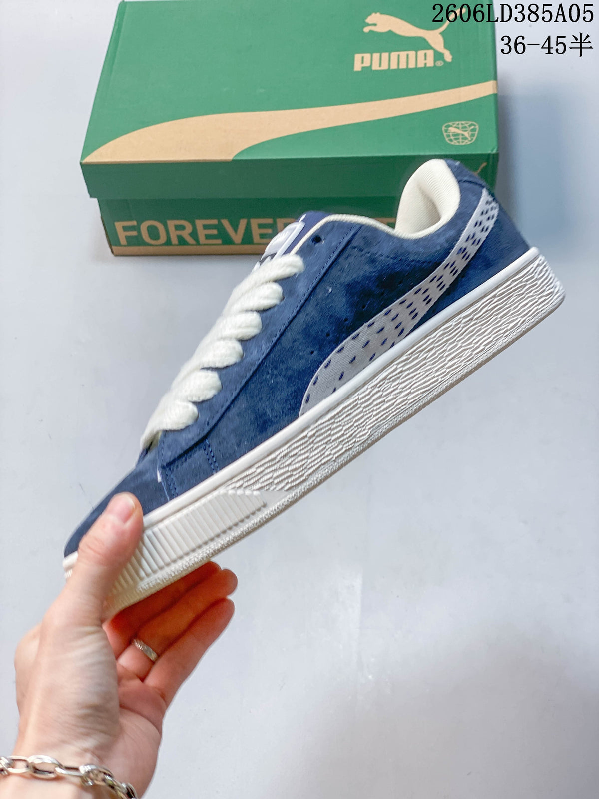 Side view of a blue PUMA sneaker with a patterned stripe and off-white sole.