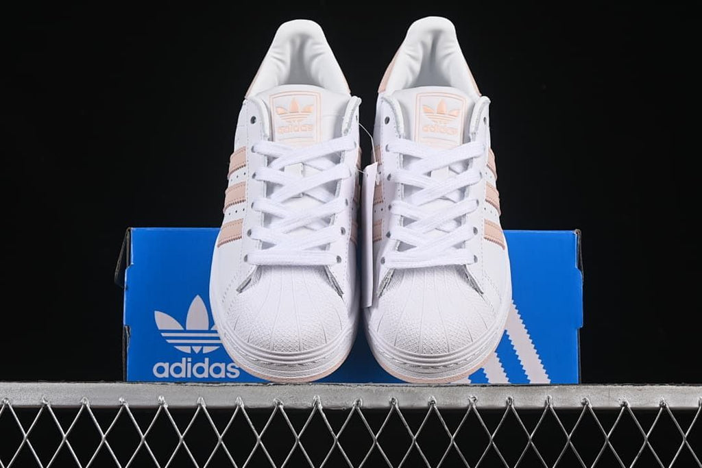 Front view of the pair of white Superstar sneakers displayed on the box.