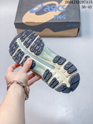 ASICS sneaker outsole showing dark traction sections, a light midsole, and the shoebox in the background.