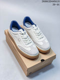 Pair of white DESCENTE low-top sneakers with light gray toe panels, navy lining, white laces, and gum-colored soles, shown on a box.