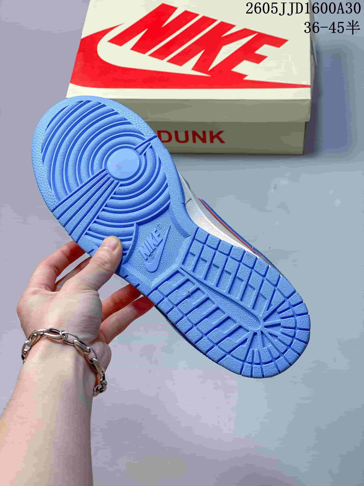 Blue rubber outsole of a Nike SB Dunk Low sneaker, with a shoe box in the background
