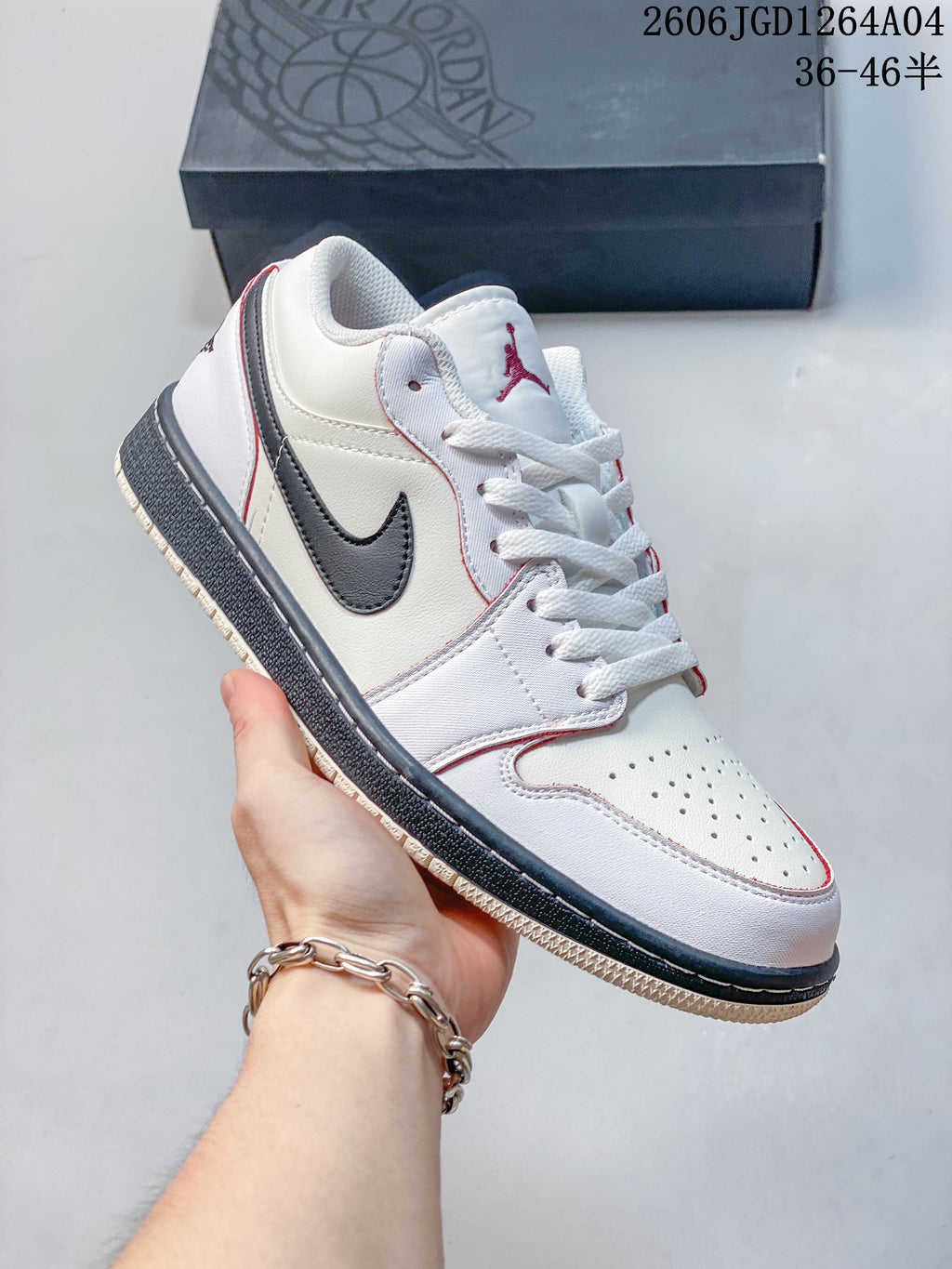 Side view of a white low-top sneaker with dark side accents and red detailing