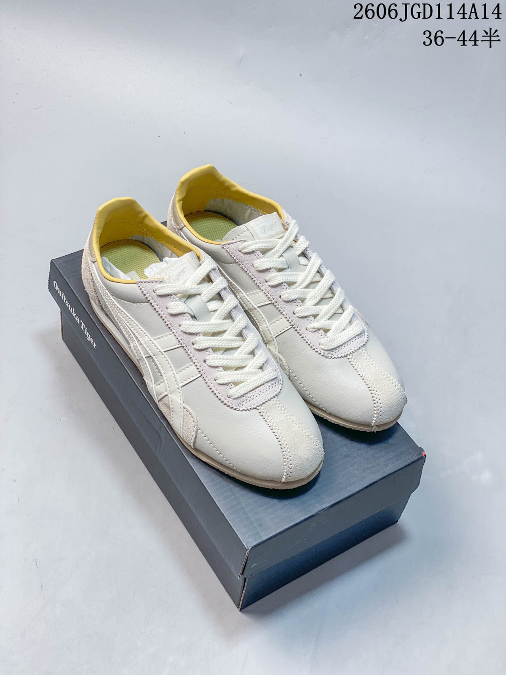 Pair of light-colored Onitsuka Tiger Runspark sneakers with pale yellow lining, shown on a branded shoe box