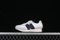 Side view of a white and light gray New Balance 327 kids’ sneaker with a navy side accent.