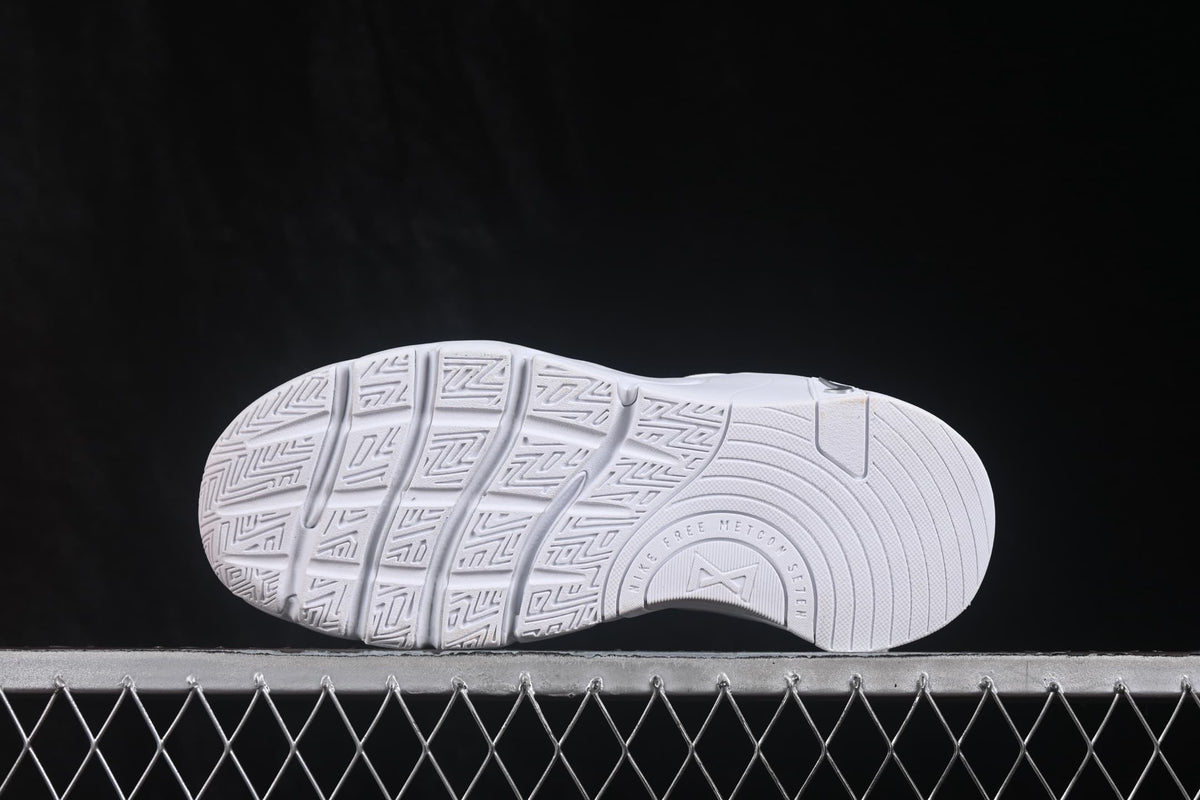 Outsole view showing the segmented tread pattern and molded sole design of the white sneakers.