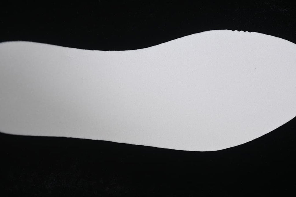 Plain white shoe insert shown against a dark background.