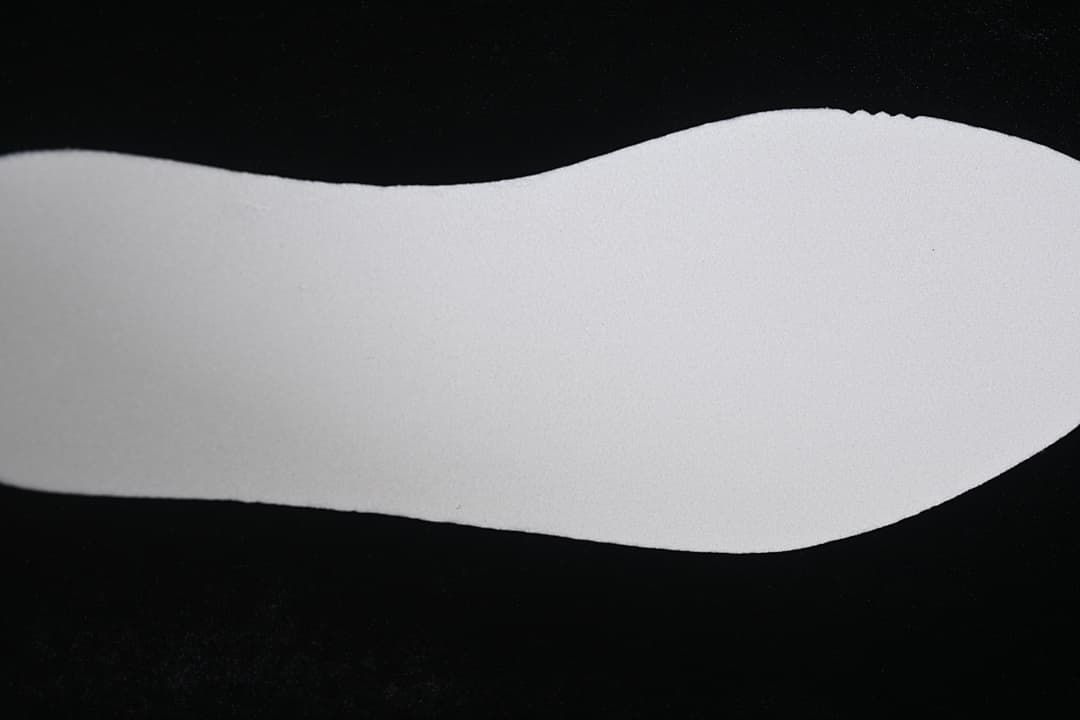 Plain white shoe insert shown against a dark background.