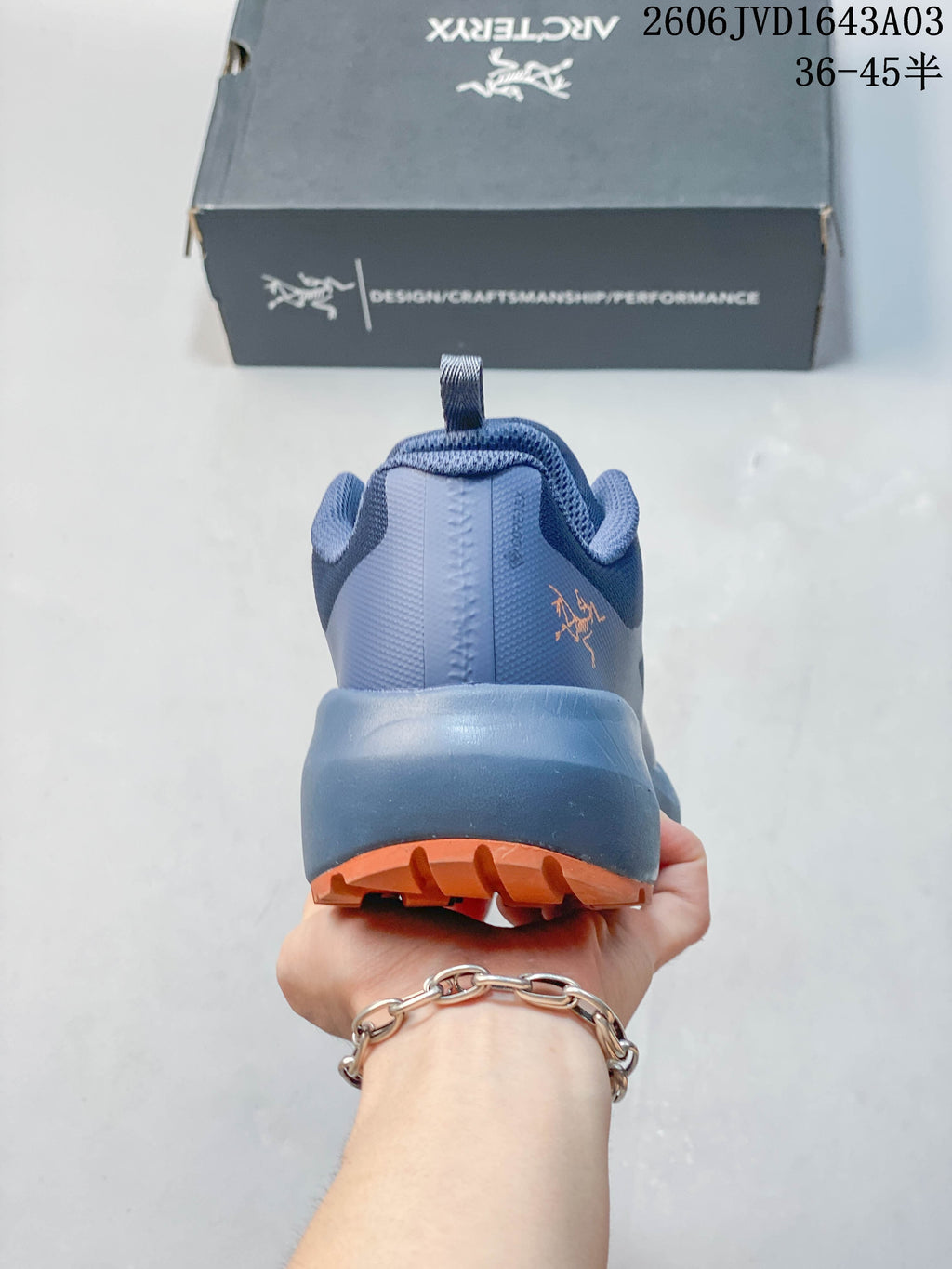 Rear view of a blue-toned outdoor shoe with orange outsole