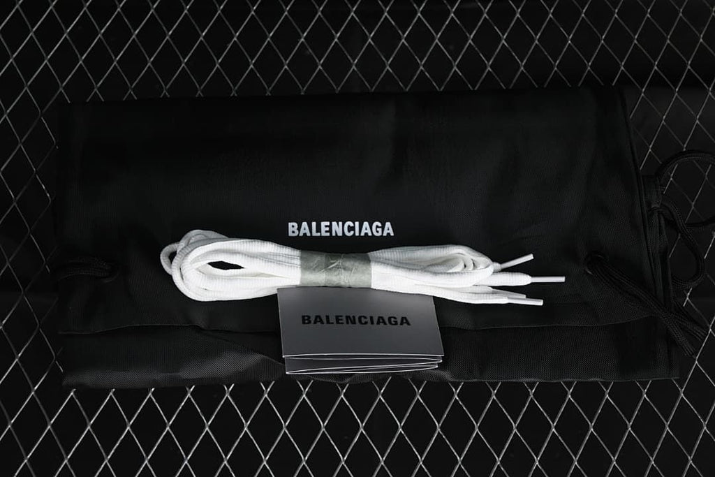 White spare laces and printed shoe accessories displayed with a black branded dust bag.