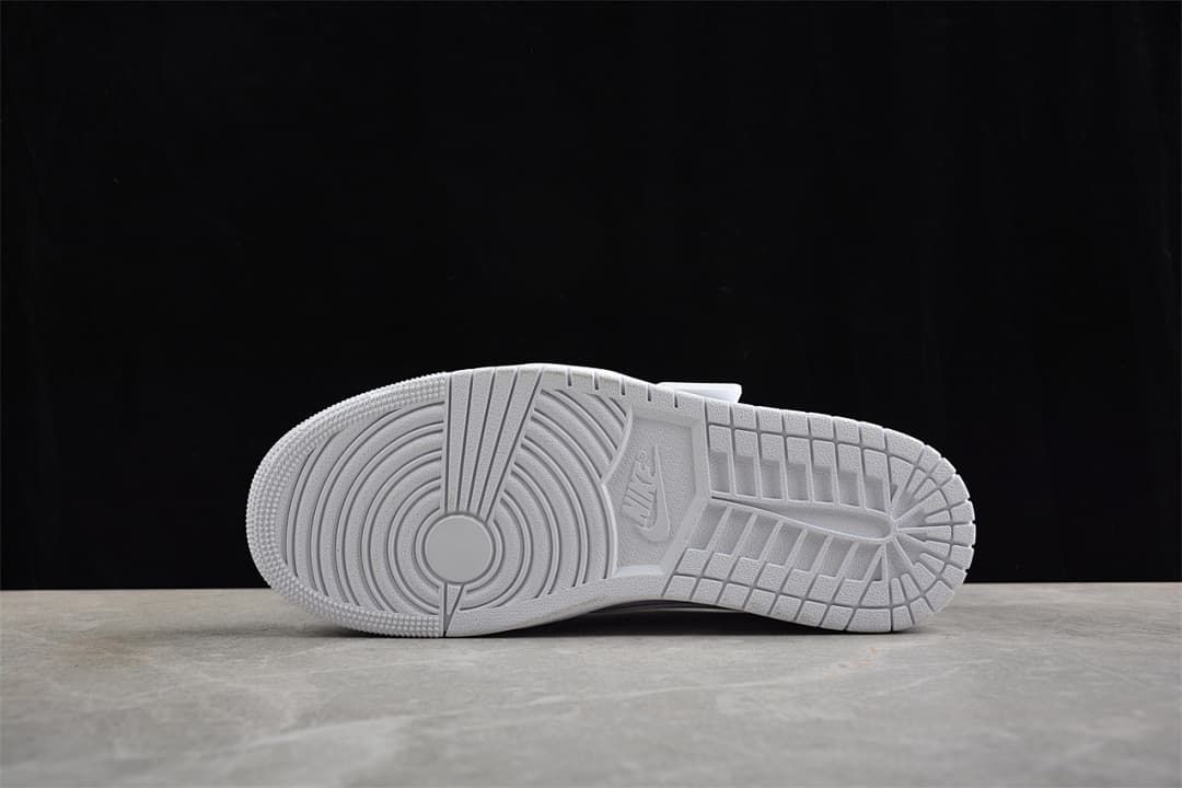 Underside of the white sneaker showing the patterned outsole