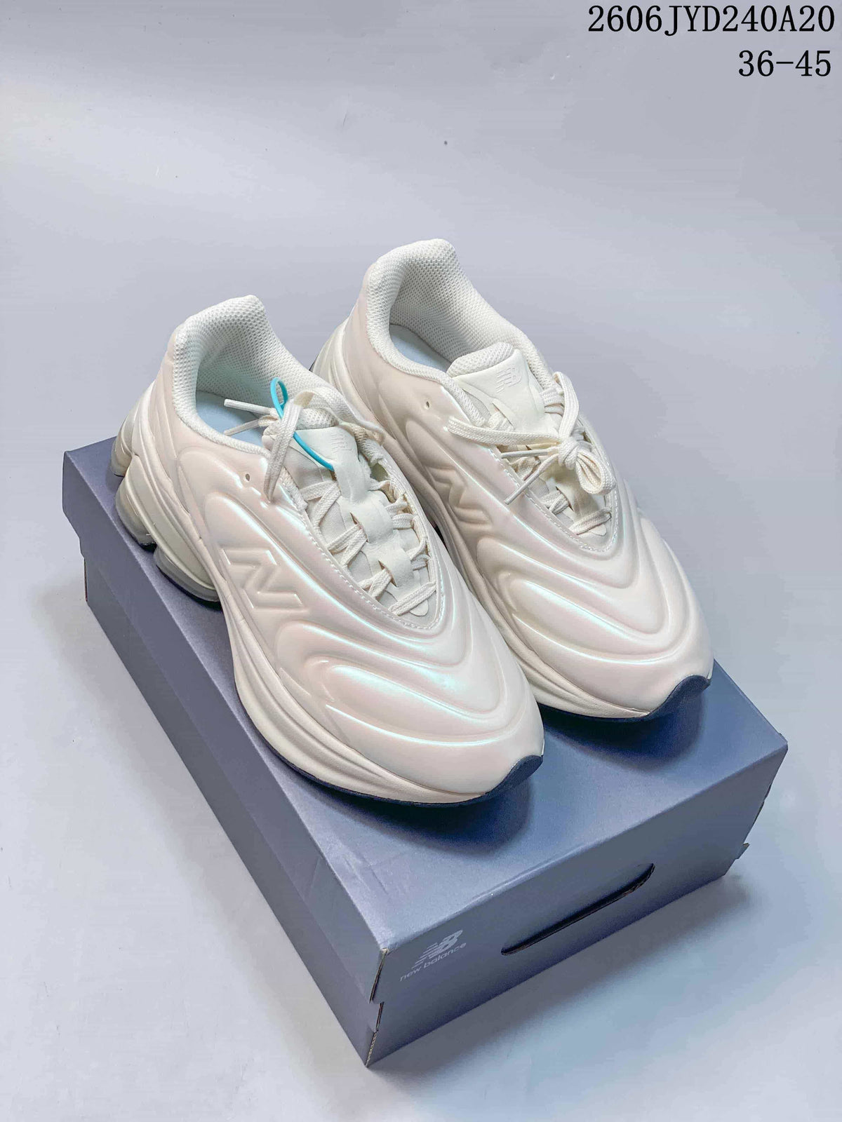 Pair of pearl-white New Balance NB5030 sneakers displayed on a shoebox.