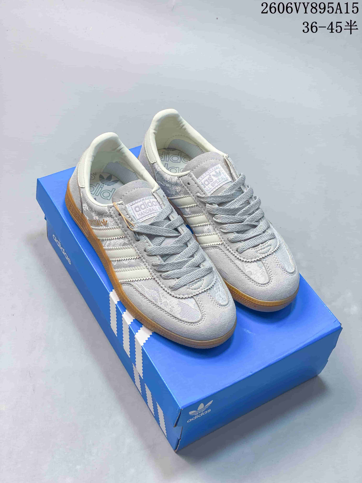 Pair of grey and beige adidas Handball Spezial Ordinals sneakers with gum-colored soles, shown on a blue shoebox