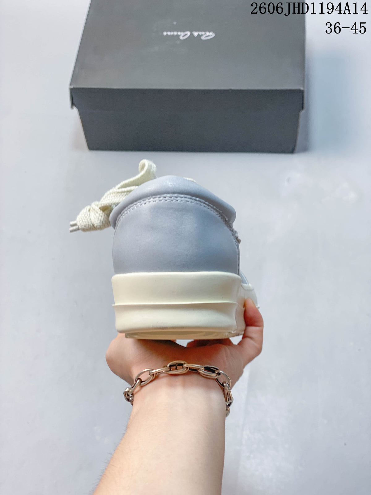 Rear view of a pale gray sneaker with a layered off-white sole