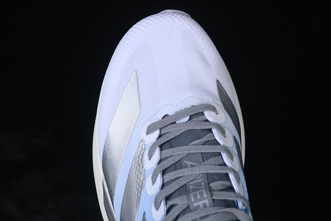 Top-down close-up of the white toe, gray laces, and silver side accents.