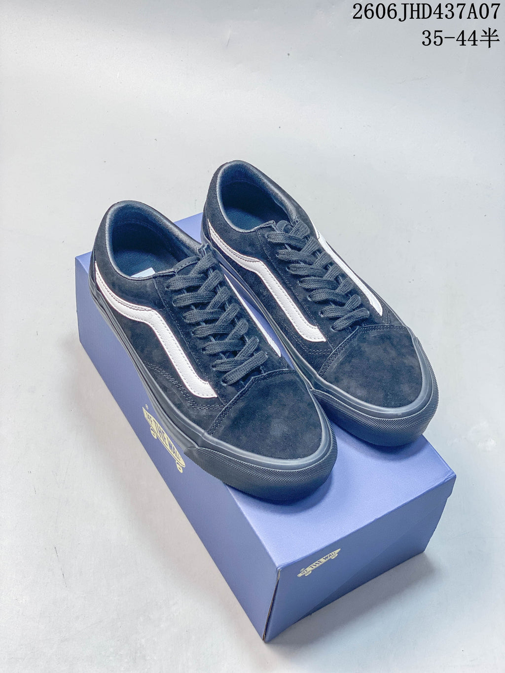 Pair of black low-top Vans Old Skool-style sneakers with white side stripes, displayed on a shoe box.