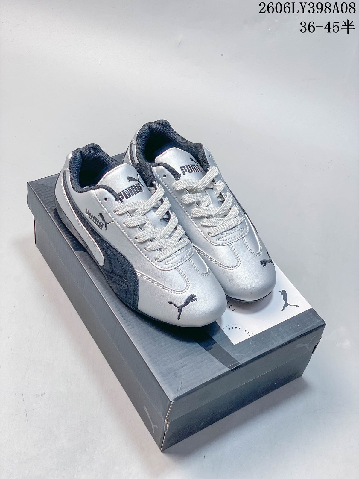 Silver PUMA Speedcat OG sneakers with dark side stripes on a box