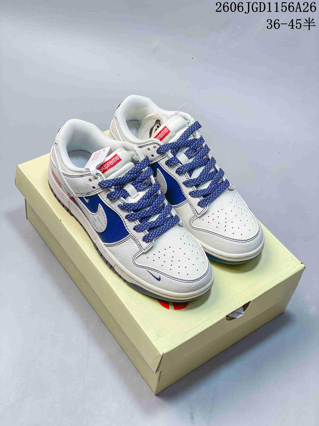 White and blue low-top Dunk-style sneakers with patterned side panels and blue laces